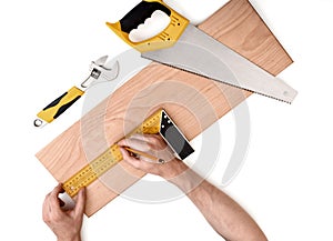 Mans hands measuring wooden plank with iron ruler, on white background