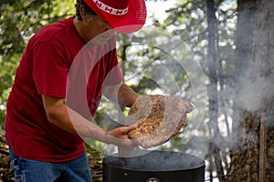 mans hands placing a large beef brisket on a smoker