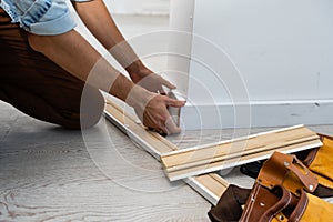 Mans hands putting white baseboard.