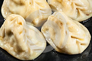 Manti oiled with butter close up on black plate