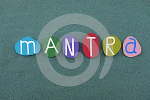 Mantra, motivating chant, usually any repeated word or phrase, text composed with multi colored stone letters over green sand