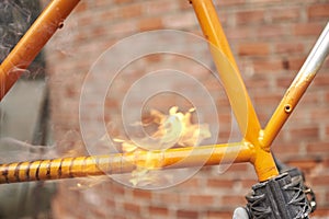 Manual bicycle renovation work, paint removal process using a torch fire