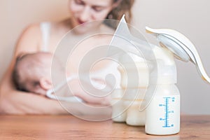 Manual breast pump and mother feeding a newborn baby