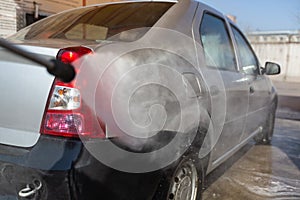 Manual car wash with pressurized water in car wash outside. Concept of summer car washing and cleaning car using high