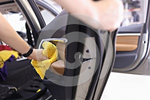 Manual cleaning of interior door panel of car with microfiber cloth closeup