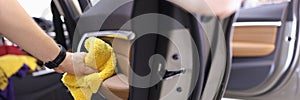 Manual cleaning of interior door panel of car with microfiber cloth closeup