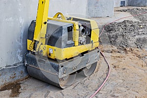 Manual compact asphalt roller for tamping soil at a construction site