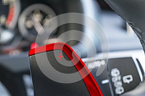 Manual gear changing stick on a car`s steering wheel, car interior details.