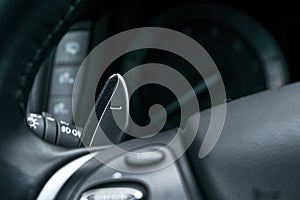 Manual gear changing stick on a car`s steering wheel, Modern car interior details.