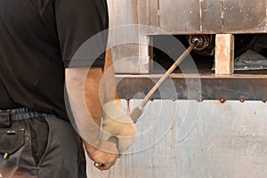 Manual glass production by glassblowing by worker at the factory. Man holding a vase in a muffle furnace