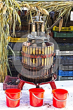 Manual grape crushing machine on with three red buckets