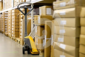 Manual Pallet Jack Waiting Amidst Cardboard Boxes in a Warehouse Aisle