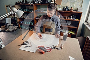 Manual production of shoes in the workshop the shoemaker begins with the preparation of a drawing from paper on the