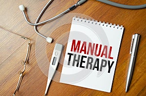 Manual therapy word on the white notepad on the wooden desk