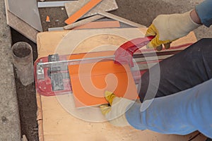 Manual tile cutter. A worker cuts a tile with a tile cutter top view. Laying of ceramic tiles.