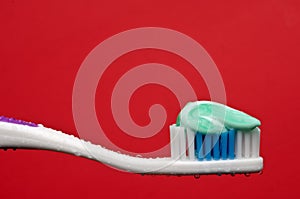 A manual toothbrush with toothpaste on red