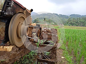 A manual tractor made of steel for plowing rice fields used to prepare land for rice cultivation.