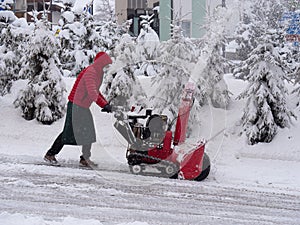 Manual Turbine Snowplow with Motor driven by an Operator dressed in Red during a day with a Heavy Snowfall