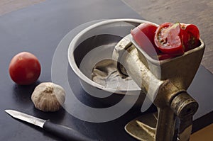 Manual vintage meat grinder, knife and vegetables on the table