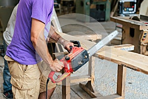 Manual wood concept. Profile side view cropped photo of cabinetmaker handyman tradesman holding chainsaw in hands sawing wood