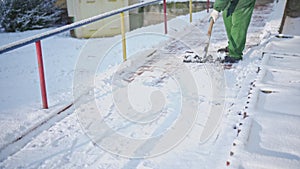 A manual worker clears snow from a sidewalk alley in a residential area in the city.