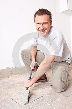 Manual worker disassembling old floor tiles