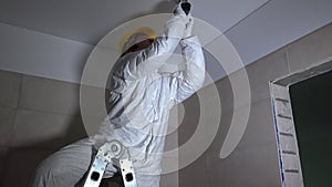 Manual worker drilling hole in ceiling plasterboard for led lighting mounting