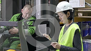 Manual worker on forklift loader and manager with clipboard at industrial warehouse. colleagues