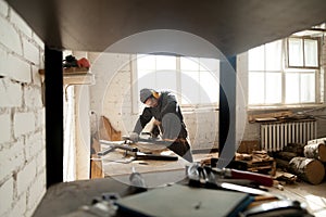 Manual worker grinding metal steel objects in workshop with tool