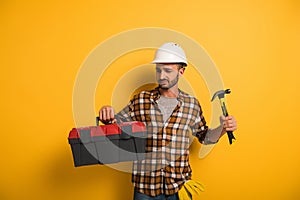 Manual worker in hardhat holding toolbox