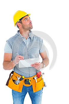 Manual worker looking away while writing on clipboard