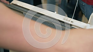 Manual worker making knitted texture on weaving machine at textile factory. Close up knitting yarn on weaving machine.