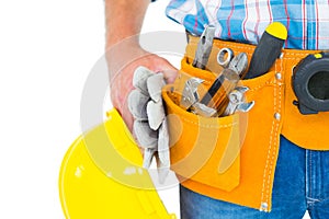 Manual worker wearing tool belt while holding gloves and helmet