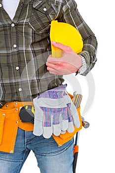 Manual worker wearing tool belt while holding helmet