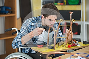 manual worker in wheelchair welding cooper pipes