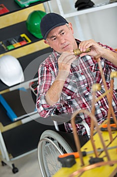 Manual worker in wheelchair working with pipes