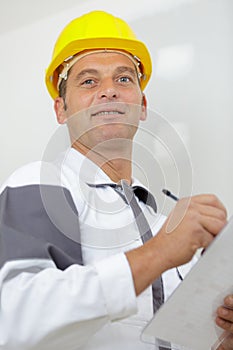 manual worker in yellow hard hat with clipboard