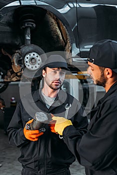 manual workers repairing car with tools