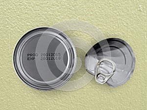 Manufacture date and expiry date printed on bottom of aluminum cans with twisted tin lid on yellow concrete kitchen counter