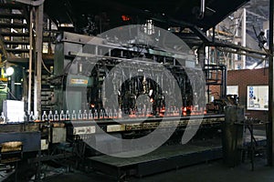 Manufacture of glass products, machine produces hot bottles by means of metal molds for blowing and pressing hot glass