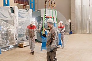 Manufacture workshop. move the crane with beam. Workers adjusts the machine in the warehouse. the production of photo