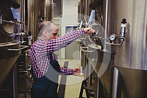 Manufacturer pouring beer in glass at brewery