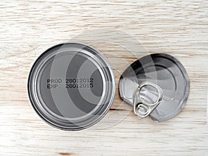 manufacturing date and expiry date printed on bottom of aluminum can and bent lid with pull ring on wooden kitchen table counter