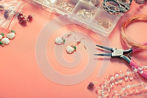 Manufacturing of earrings from metal studs, pendants with enamel, beads in a shape of peaches, crystals. Pliers, wire, box