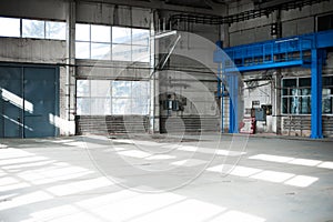 Manufacturing factory. Empty hangar building. Blue toned background. The production room with large windows and metal structures