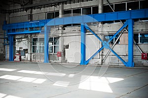 Manufacturing factory. Empty hangar building. Blue toned background. The production room with large windows and metal structures