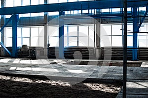 Manufacturing factory. Empty hangar building. Blue toned background. The production room with large windows and metal structures