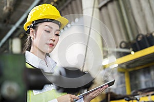Manufacturing industry. Young Female worker wearing hardhat and protection glasses with tablet look at machines in factory