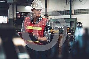 Manufacturing worker working with clipboard to do job procedure checklist .