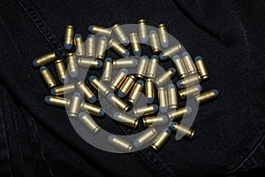 Many .45 ACP cartridges on a black fabric background